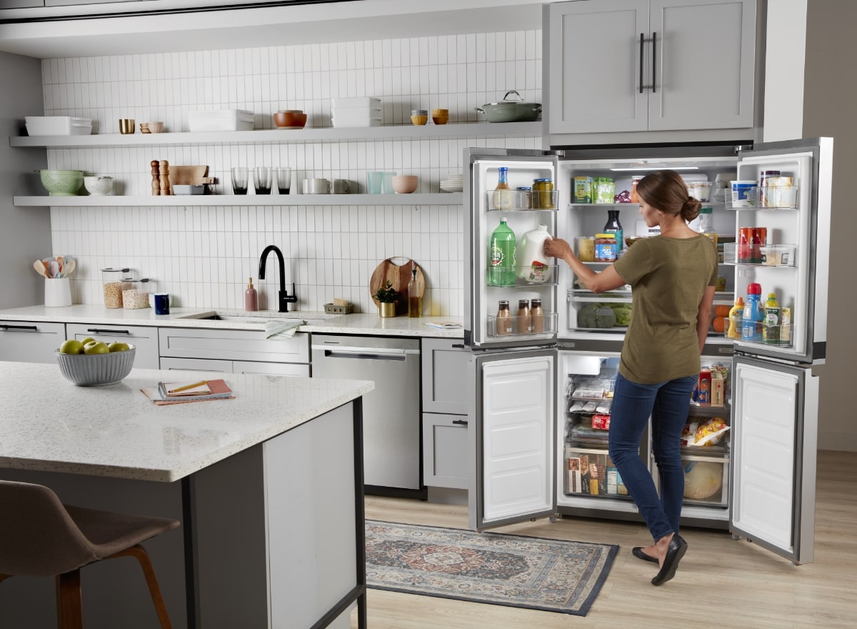 person getting milk out of a refrigerator with all doors open