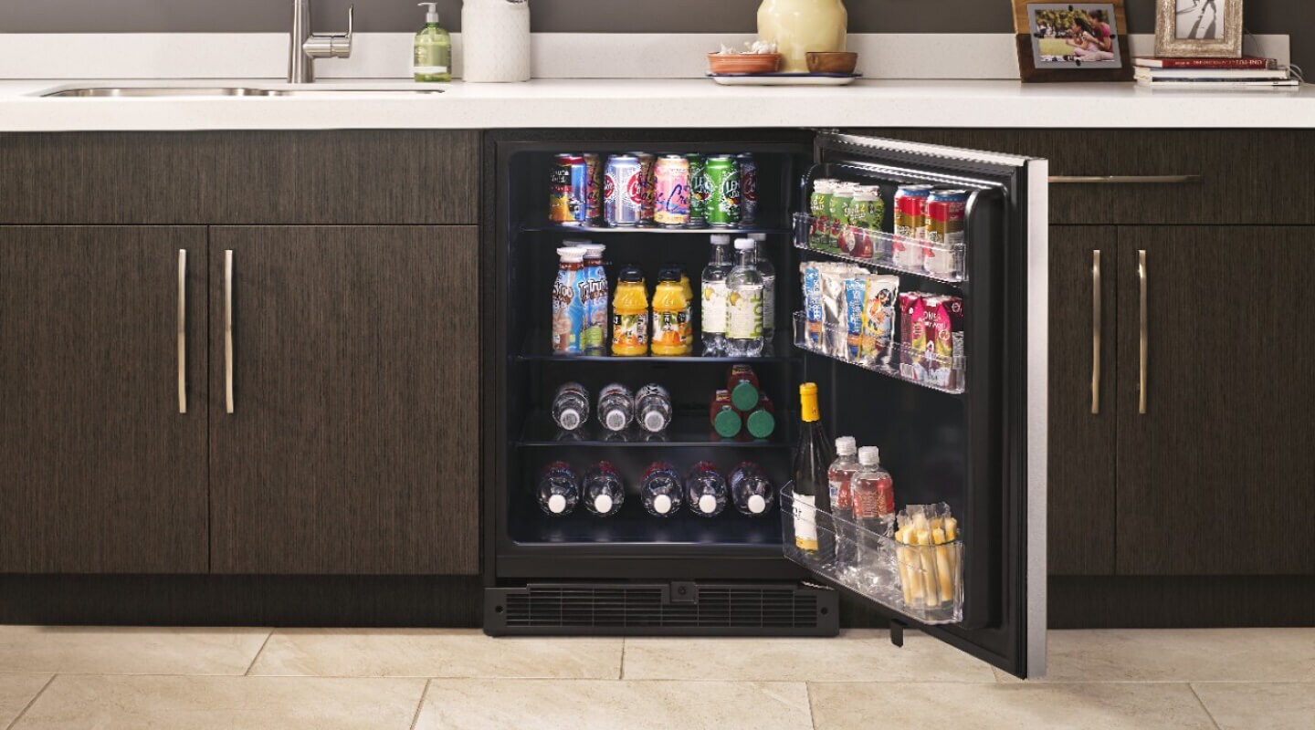 Open undercounter refrigerator stocked with beverages and snacks Open undercounter refrigerator stocked with beverages and snacks