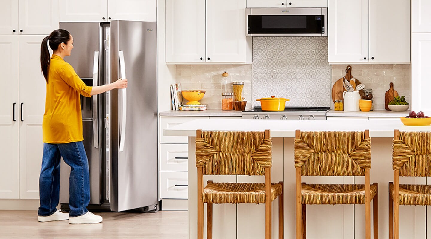 Person opening a stainless steel Whirlpool® Side-by-Side refrigerator Person opening a stainless steel Whirlpool® Side-by-Side refrigerator