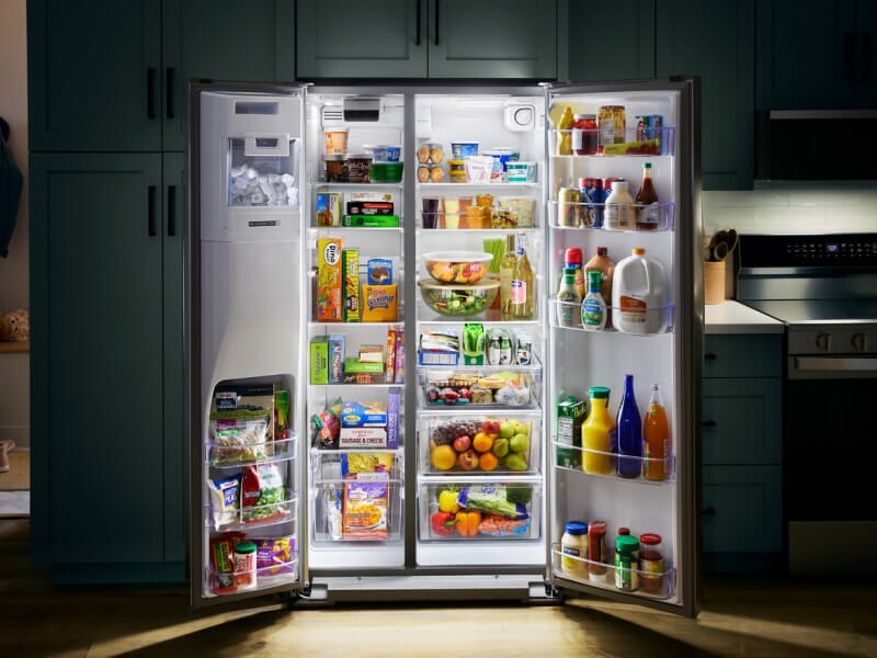 Open side-by-side refrigerator stocked with fresh and frozen foods Open side-by-side refrigerator stocked with fresh and frozen foods