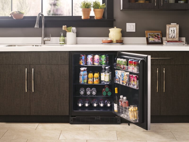 Open undercounter refrigerator stocked with beverages and snacks