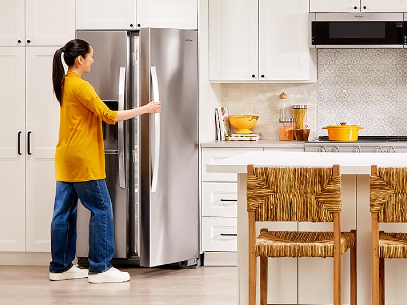 Person opening a stainless steel Whirlpool® Side-by-Side refrigerator Person opening a stainless steel Whirlpool® Side-by-Side refrigerator