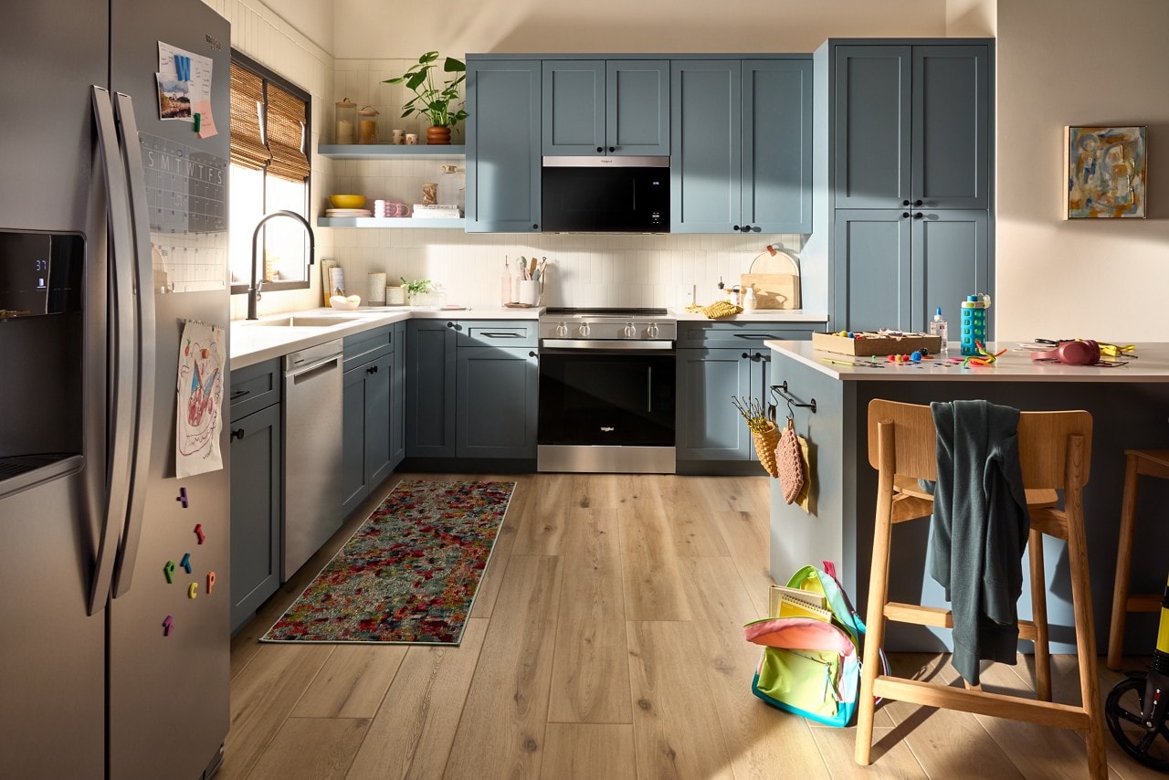 A suite of WhirlpoolÂŽ stainless steel appliances in a cornflower blue kitchen