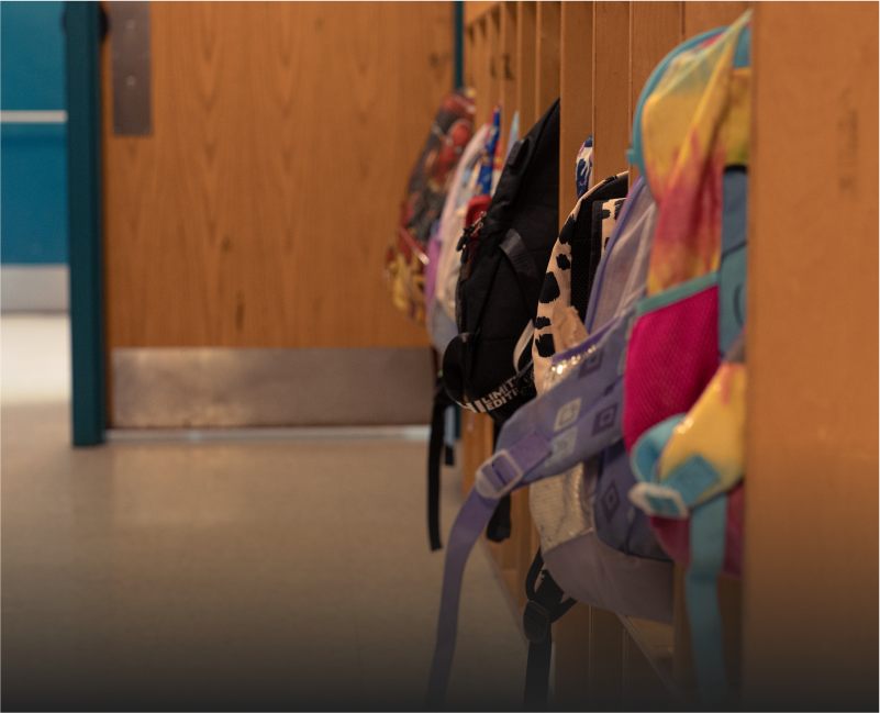 A row of children's backpacks in a cubby area