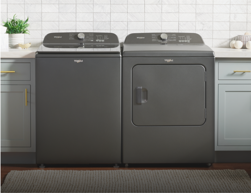 A dark gray Whirlpool® Top Load Washer and Dryer in a laundry room