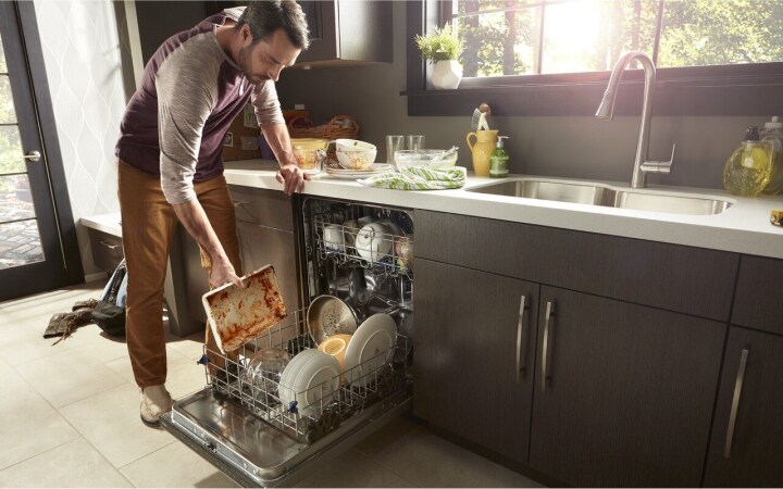 Man loading a dishwasher in a modern kitchen