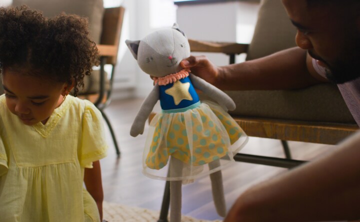 Father handing stuffed animal to daughter