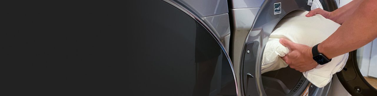 Man putting pillow into a washing machine