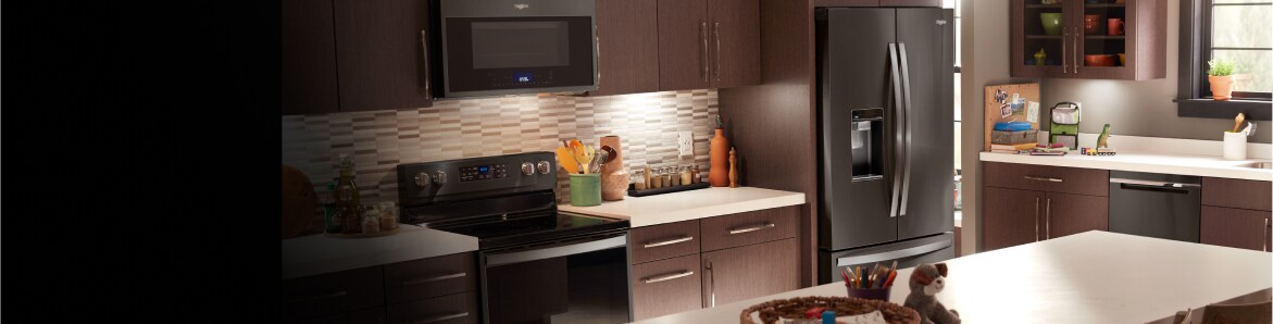 A sleek kitchen featuring a Whirlpool® black stainless steel refrigerator.