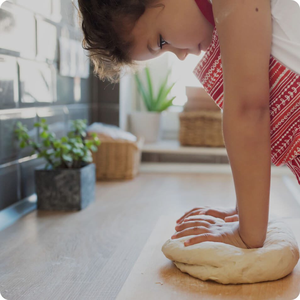 A child kneading dough on a kitchen countertop