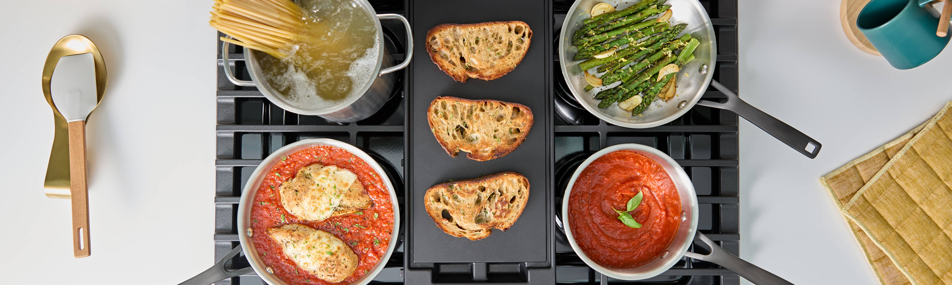 Birds-eye view of food cooking on a gas cooktop and griddle attachment
