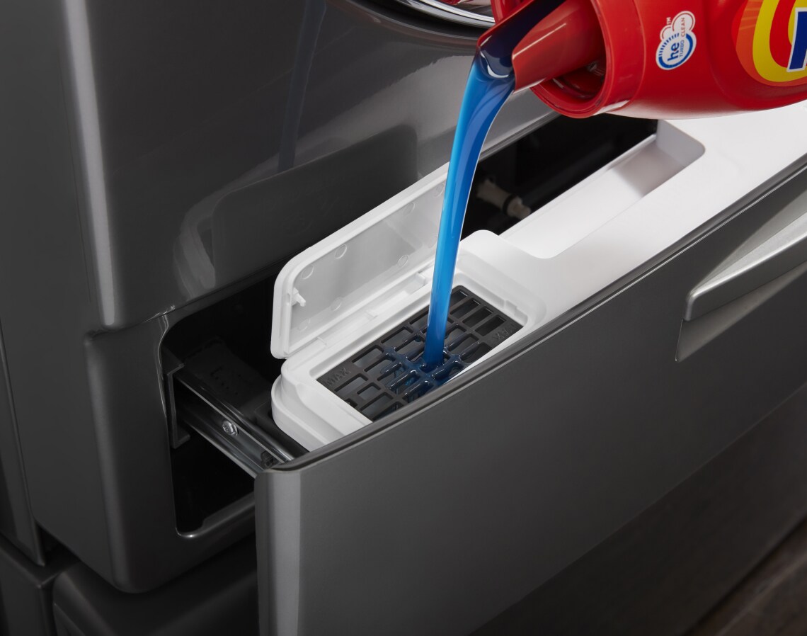 Close-up of detergent being added to a front load washer and dryer set.