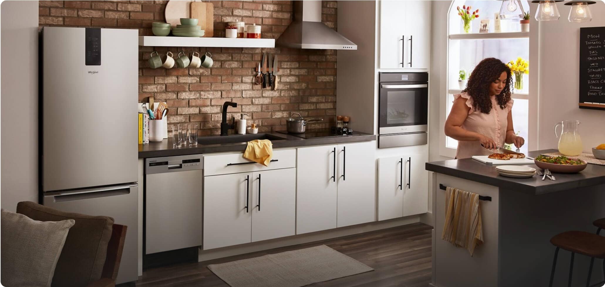 A woman preparing food on a counter in a kitchen with light cabinets and a Whirlpool® Small Space Wall Oven, Electric Cooktop and Bottom-Freezer Refrigerator