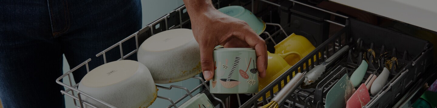 A person putting a cup inside of a Whirlpool® 3rd Rack Dishwasher