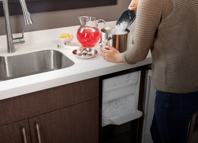 A person placing ice into an ice bucket