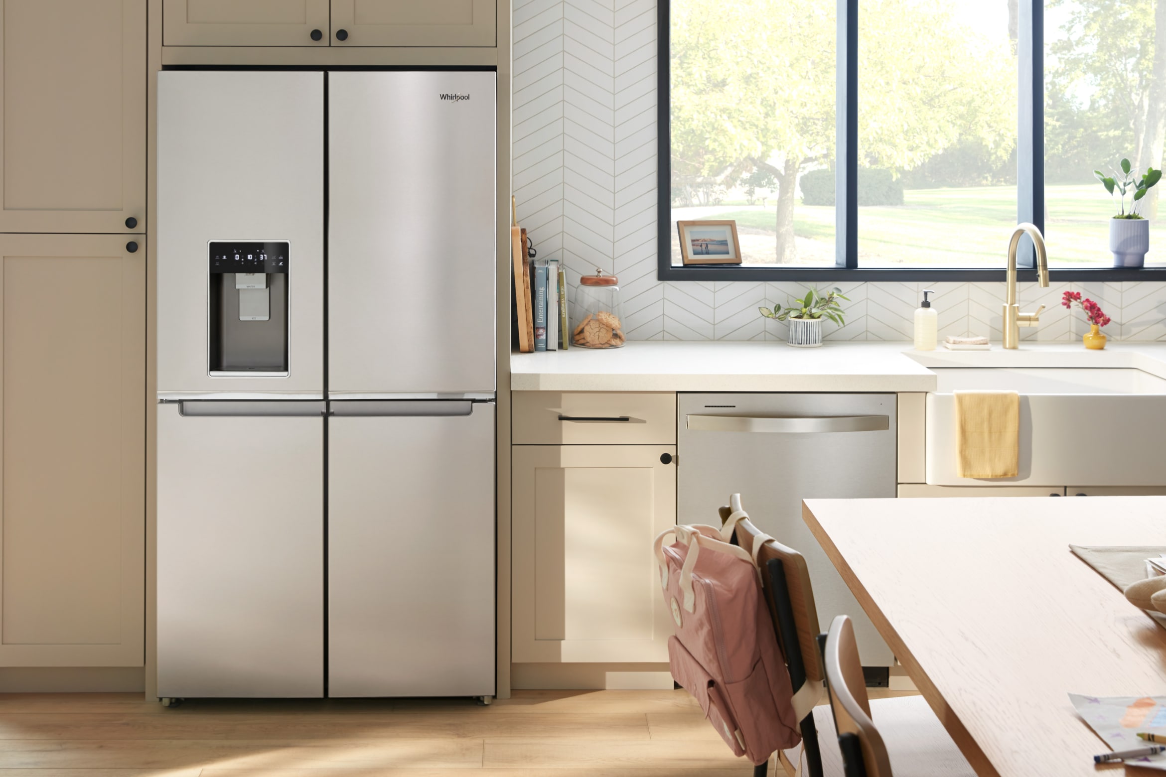 A four door refrigerator and dishwasher in a bright kitchen