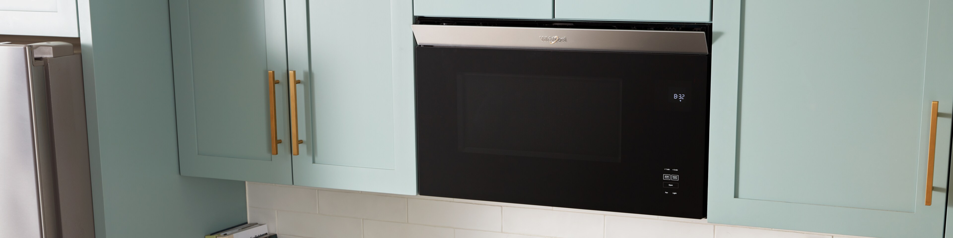 A Whirlpool® Low Profile Microwave in a sleek, white, modern kitchen