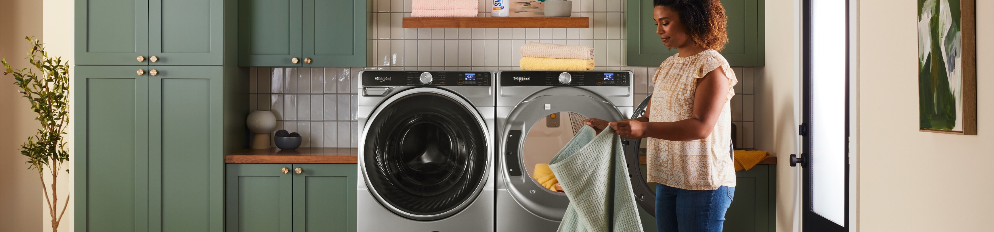 A person unloading laundry from a Whirlpool® Front Load Washer and Dryer Pair