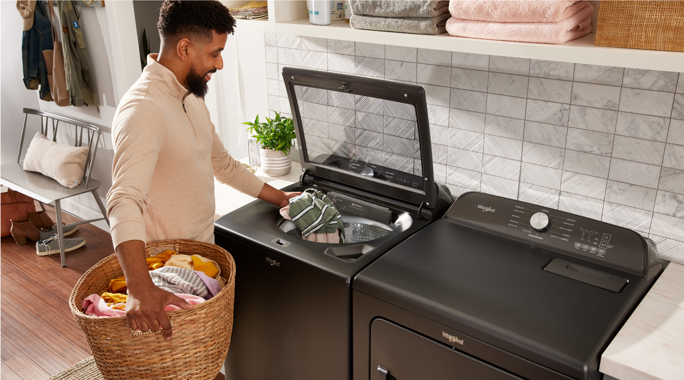 A person adding clothes to a top load washer