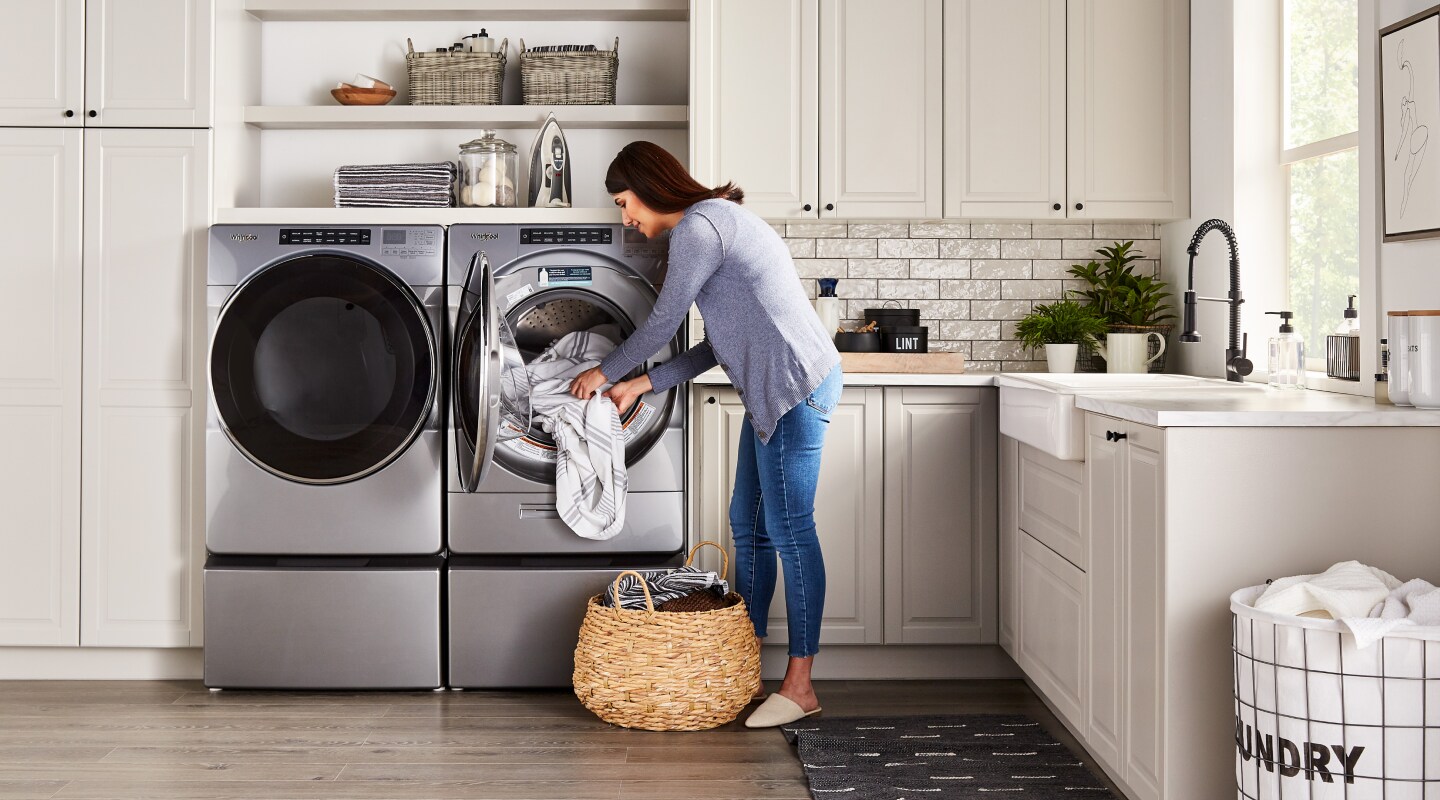 Woman loading laundry in a stainless steel Whirlpool® dryer Woman loading laundry in a stainless steel Whirlpool® dryer