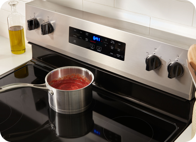 A pot a pasta sauce simmering on a stovetop.