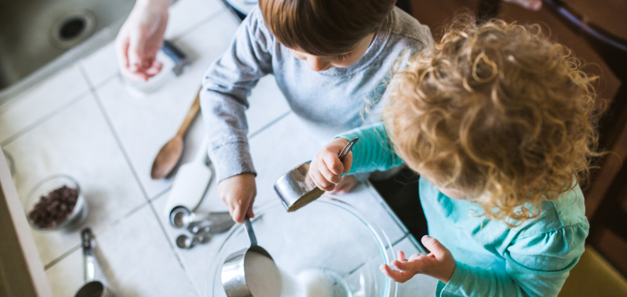 Two kids helping mix ingredients in the kitchen