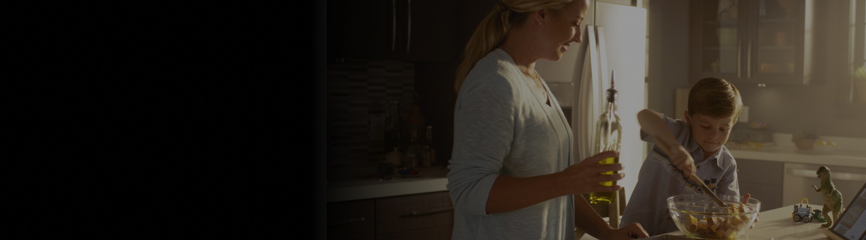 Mom and son using a tablet, mixing bowl and sheet pan on the countertop to make a recipe together.