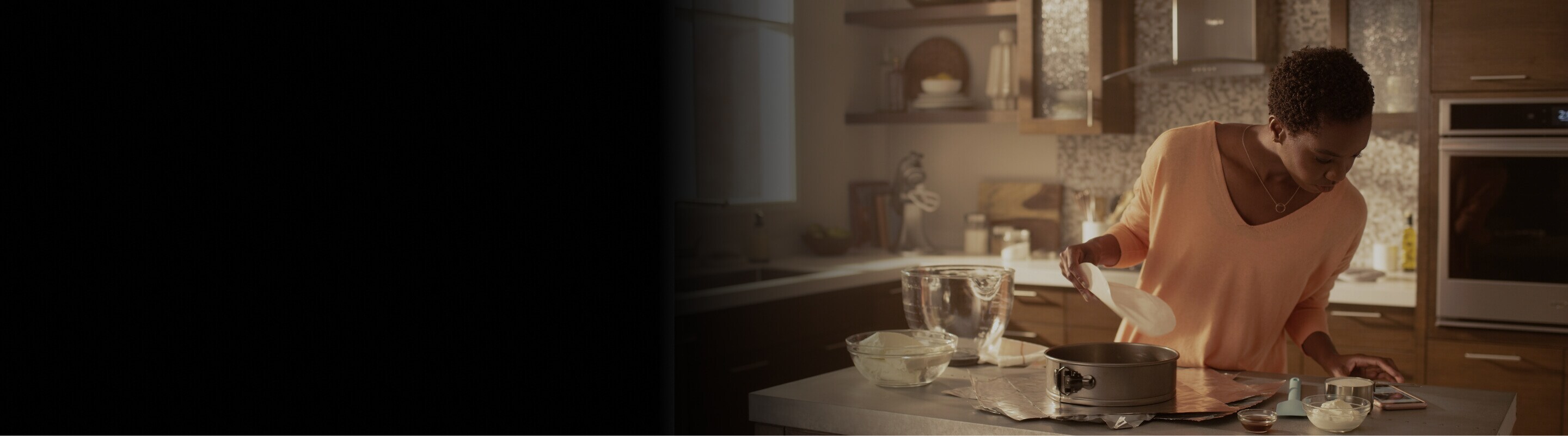 Woman in a kitchen following a recipe on her cell phone.
