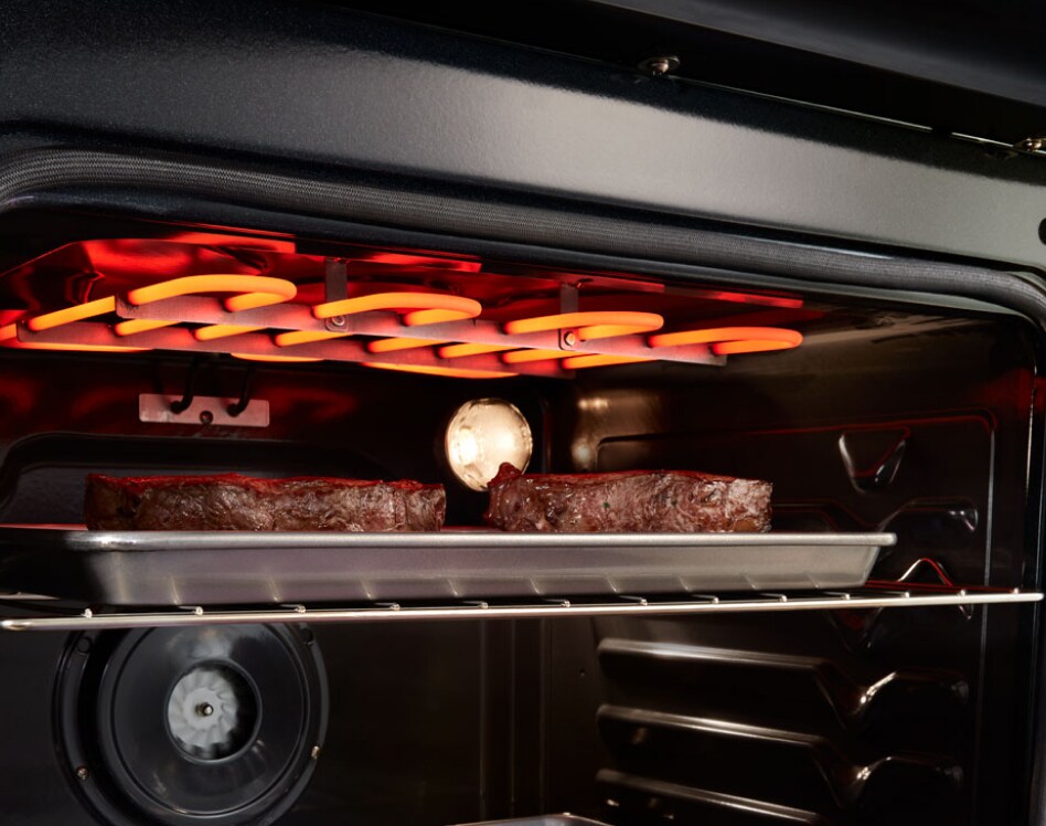 Two steaks broiling in open oven