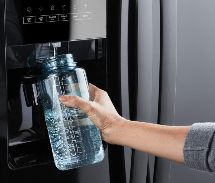 A person filling a reusable water bottle from a Whirlpool® refrigerator.