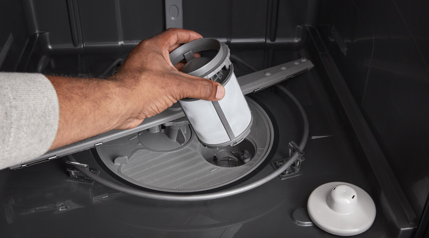 Person replacing dishwasher filter Person replacing dishwasher filter
