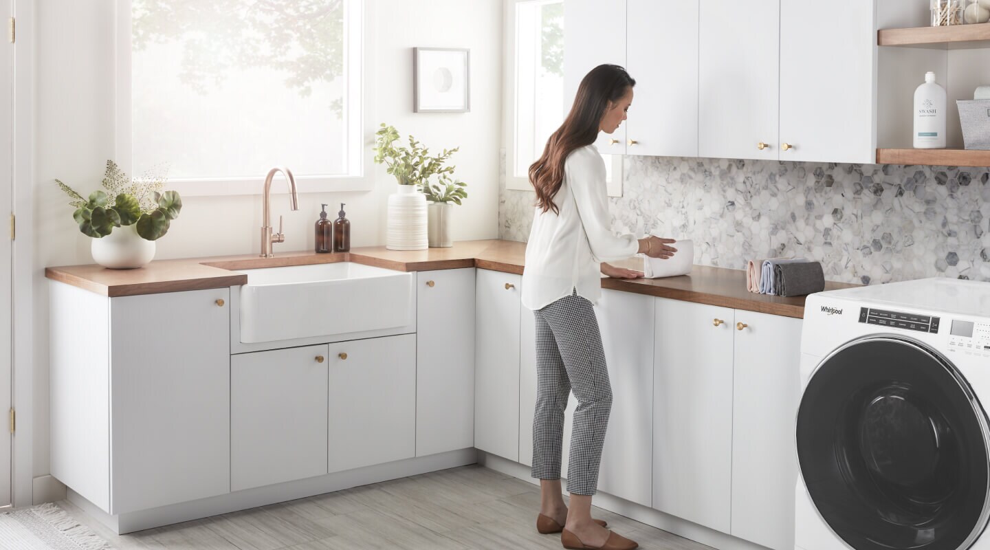 Person standing at the counter in a white laundry room Person standing at the counter in a white laundry room