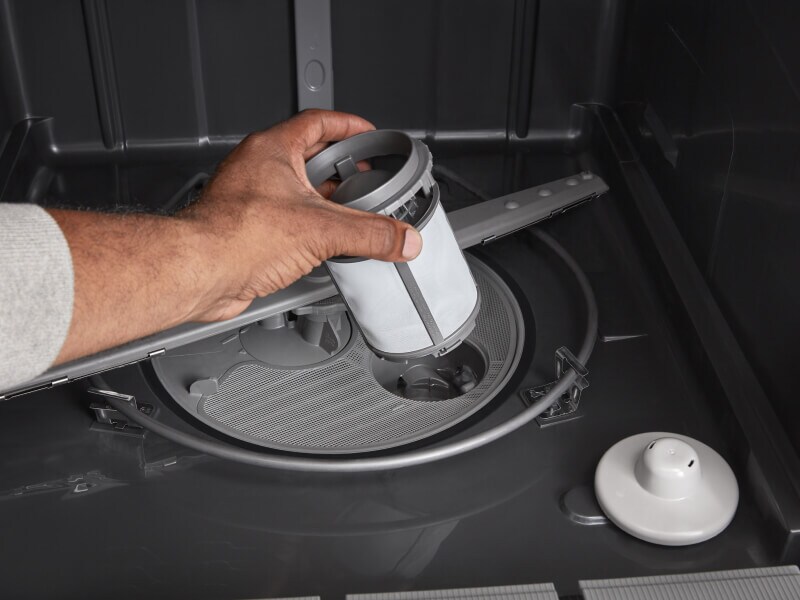 Person replacing dishwasher filter