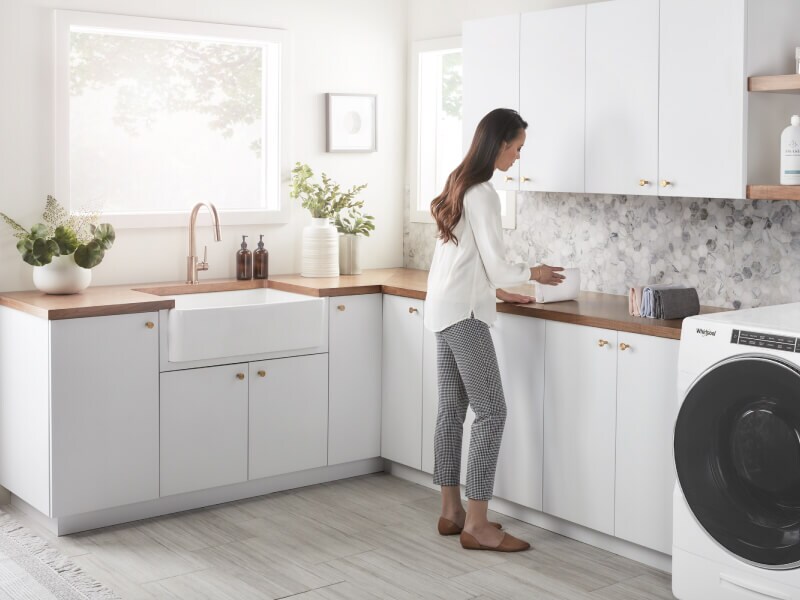 Person standing at the counter in a white laundry room Person standing at the counter in a white laundry room