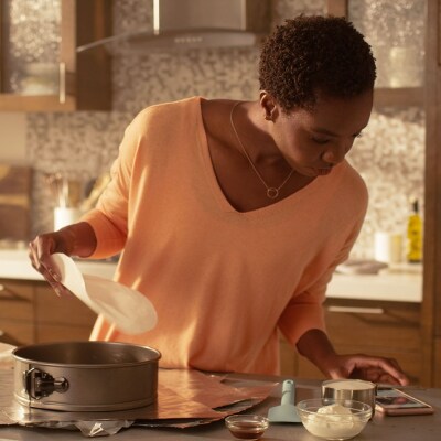 Person reviewing recipe on phone while preparing a springform pan
