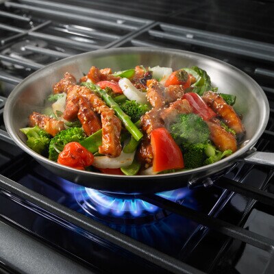 Vegetable stir fry in a skillet on a gas stove top burner