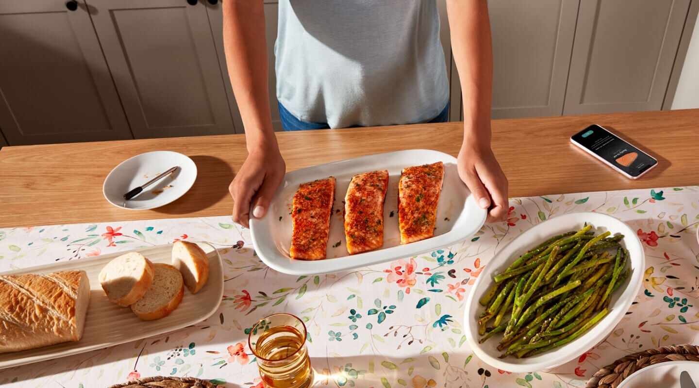 Birds-eye view of person holding platter with cooked salmon next to prepared bread and asparagus Birds-eye view of person holding platter with cooked salmon next to prepared bread and asparagus