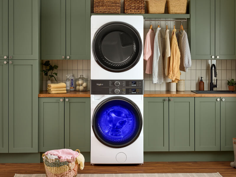 A stackable washer and dryer with the UV light on in a laundry room