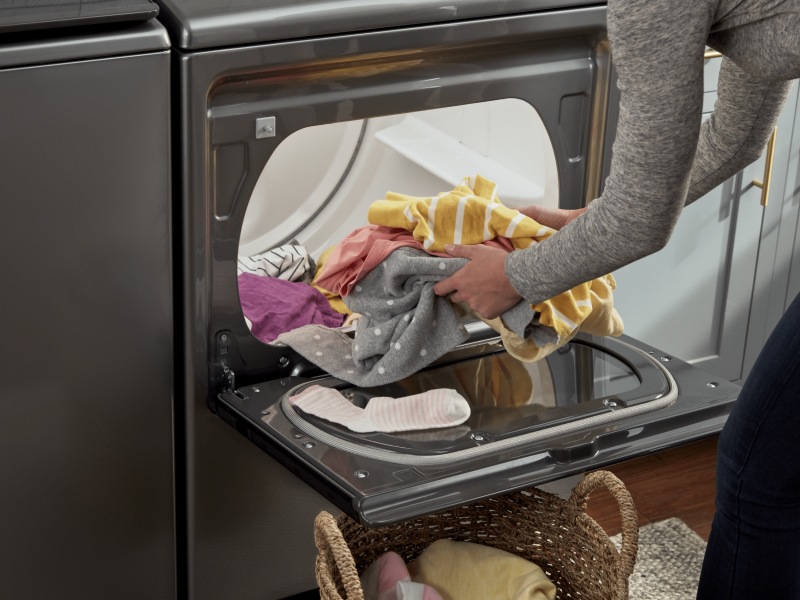 Person loading clothes into a Whirlpool® dryer Person loading clothes into a Whirlpool® dryer
