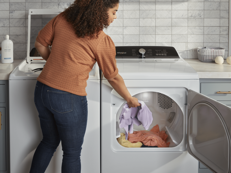 Person loading towels into a Whirlpool® dryer Person loading towels into a Whirlpool® dryer
