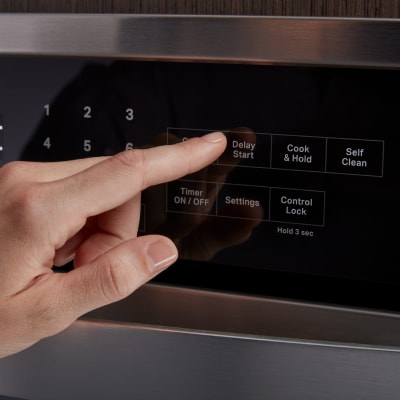 A person selecting the Delay Start option on an oven