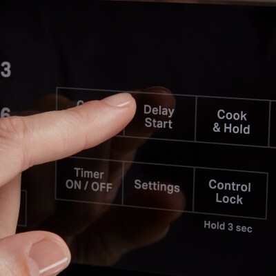  A person selecting the Delay Start option on an oven