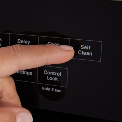 A person selecting the Self Clean option on an oven
