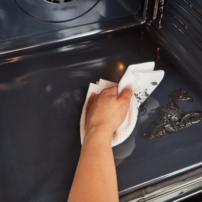 A person cleaning an oven on Steam Clean