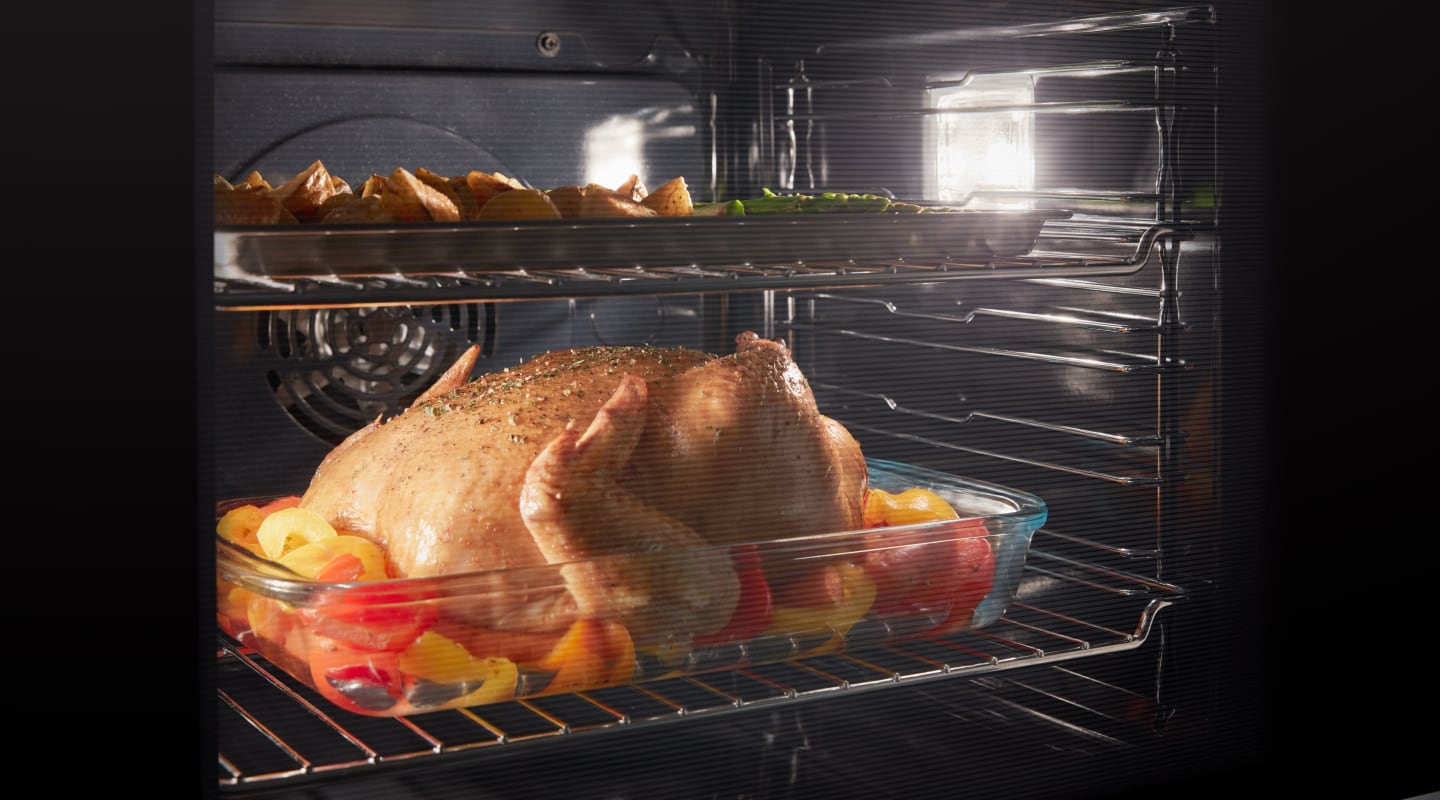 Chicken and vegetables roasting in an oven Chicken and vegetables roasting in an oven