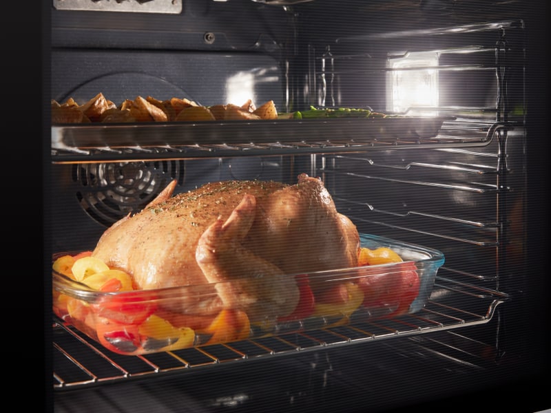 Chicken and vegetables roasting in an oven Chicken and vegetables roasting in an oven