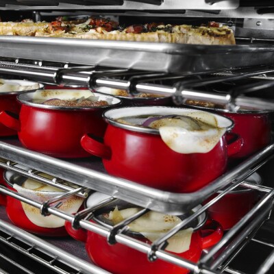 The inside of an oven with food cooking on all three racks