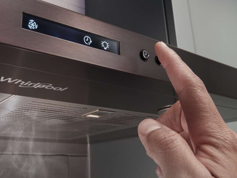 Person selecting a button on a range hood Person selecting a button on a range hood