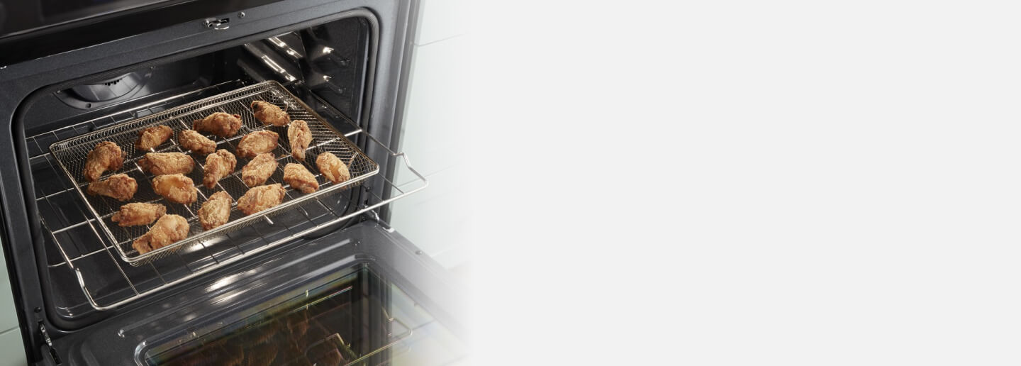 Chicken wings in an air fry basket in an oven