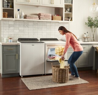 Person loading laundry into a top load dryer